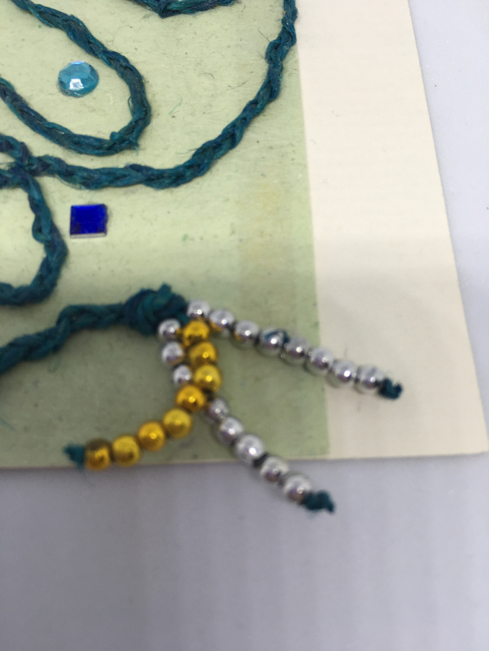 Nærbillede af gammelt kort med flettet snor og perler.